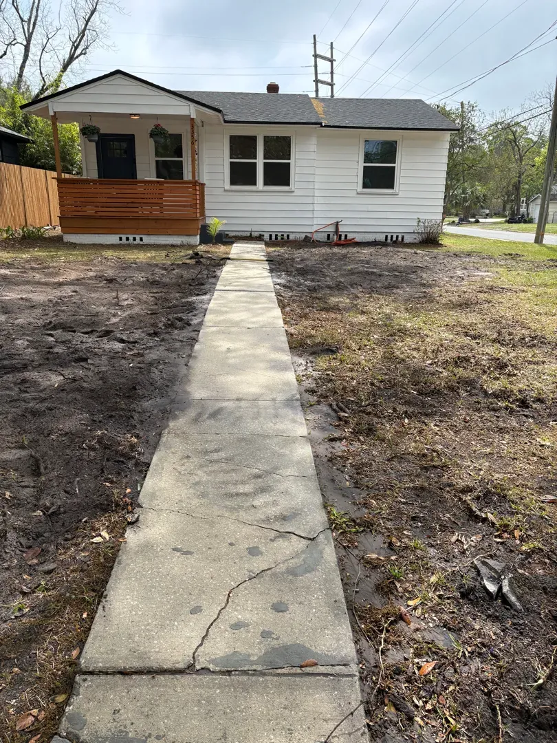 Backfilled trench along the front walkway after sewer line replacement, house in background